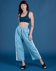 Alex is 5’8” and wearing XXS Painted Drop Pocket Cargo Pants in Baby Blue paired with lagoon Mini Tank
