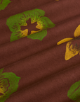 Floral Painted Work Pants in Brown fabric detail close up. Brown pant with green and yellow paintstamped flowers
