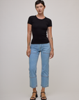 Alex is wearing Baby Tee in Basic Black and light wash carpenter jeans