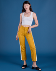 Alex is 5’8” and wearing XXS Painted Work Pants in Mustard Yellow paired with vintage tee white Cropped Tank