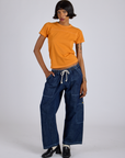 Kira is wearing Jr. Varsity Tee in Creamsicle Orange and dark wash Denim Drop Pocket Pants