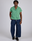 Isaac is wearing Pantry Button-Up in Seafoam Green and dark wash Denim Drop Pocket Pants