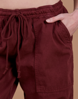 Close up of Alex's hand in the front pocket of Drop Pocket Cargo Pants in Red Wine