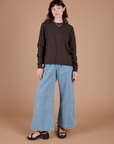 Alex is wearing Long Sleeve Burly Tee in Espresso Brown paired with light wash Indigo Wide Leg Trousers