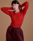 Alex is wearing Gingham Long Sleeve Baby Tee in Mustang Red tucked into red wine Drop Pocket Cargo Pants