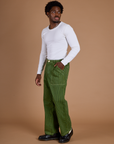 Angled front view of Railroad Denim Work Pants in Gross Green Overdye and vintage tee white Long Sleeve Baby Tee on Isaac