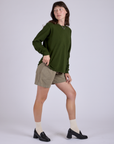 Side view of Pleated Trouser Shorts in Khaki Grey and evergreen Long Sleeve Burly Tee on Alex