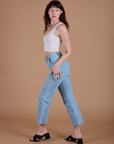 Side view of Carpenter Jeans in Light Wash and vintage tee white Cropped Tank