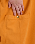 Close up of Juliet's hand above the Drop Pocket Cargo Pants in Creamsicle Orange side pant leg pocket