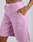 Close up of Kira's hand in the front pocket of Longline Work Shorts in Lilac Purple