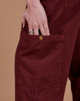 Close up of Alex's hand in the side pant leg pocket of Drop Pocket Cargo Pants in Red Wine