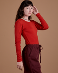Angled front view of Gingham Long Sleeve Baby Tee in Mustang Red on Alex