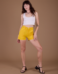 Alex is 5’8” and wearing XXS Classic Work Shorts in Sunshine Yellow paired with a vintage tee white Cropped Tank