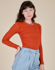 Angled front view of Long Sleeve Baby Tee in Chili Red on Alex