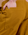 Close up of Alex's hand in the back pocket of Drop Pocket Cargo Pants in Spicy Mustard
