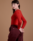 Angled back view of Gingham Long Sleeve Baby Tee in Mustang Red on Alex