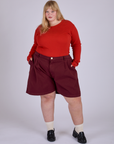 Juliet is 5’7” and wearing 2XL Pleated Trouser Shorts in Red Wine paired with Long Sleeve Gingham Baby Tee in Mustang Red