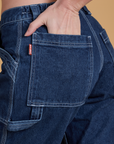 Close up of Alex's hand in the back pocket of Mid-Rise Carpenter Jeans in Dark Wash
