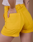 Close up of Alex's hand in the back pocket of Classic Work Shorts in Sunshine Yellow