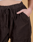 Close up of Alex's hand in the front pocket of Corduroy Drop Pocket Cargo Pants in Espresso Brown