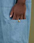 Close up of Isaac's hand in the side pant leg pocket of Denim Drop Pocket Pants in Light Wash