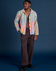 Isaac is wearing Stripe Work Jacket in Rainbow Stripe paired with espresso Work Pants