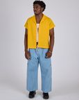 Isaac is wearing Pantry Button-Up in Sunshine Yellow and light wash Denim Drop Pocket Pants