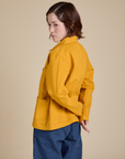 Angled back view of Denim Work Jacket in Mustard Yellow on Hana