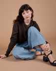 Alex is sitting on the ground and wearing Long Sleeve Burly Tee in Espresso Brown