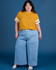 Ashley is wearing Painted Burly Tee in Mustard Yellow and light wash Wide Leg Trousers