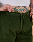 Front close up of Corduroy Drop Pocket Cargo Pants in Evergreen with Sam pulling on the drawstring