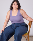 Ashley is sitting in a chair and wearing Cropped Tank Top in Faded Grape paired with dark wash Indigo Wide Leg Trousers