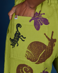 Close up of Kandia's hand in the back pocket of Paintstamped Work Pants in Froggy