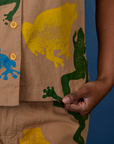 Close up of Kandia holding the bottom hem of Paintstamped Pantry Button-Up in Froggy