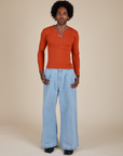 Jerrod is wearing Long Sleeve Baby Tee in Chili Red and light wash Indigo Wide Leg Trousers