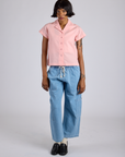 Kira is 5’10” and wearing P Pantry Button-Up in Baby Pink paired with light wash Denim Drop Pocket Pants