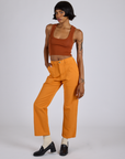 Angled front view of Work Pants in Creamsicle Orange and burnt terracotta Cropped Tank on Kira
