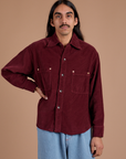 Anthony is wearing a buttoned up Cropped Corduroy Overshirt in Red Wine