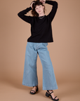Alex is wearing Long Sleeve Burly Tee in Basic Black with light wash Indigo Wide Leg Trousers