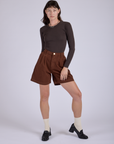 Alex is wearing Pleated Trouser Shorts in Fudgesicle Brown and Long Sleeve Baby Tee in Espresso