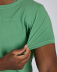 Close up of Isaac tugging the sleeve of Jr. Varsity Tee in Seafoam Green