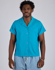 Isaac is wearing a buttoned up Pantry Button-Up in Hawaiian Blue