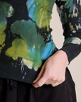 Long Sleeve Baby Tee in Green Pool bottom close up with Alex holding the hem