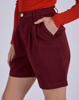Side view close up with Alex's hand in the front pocket of Pleated Trouser Shorts in Red Wine