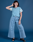 Alex is wearing Painted Burly Tee in Baby Blue and light wash Wide Leg Trousers
