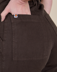 Close up of Alex's hand in the back pocket of Short Sleeve Jumpsuit in Espresso Brown