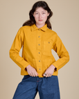 Alex is wearing a buttoned up Denim Work Jacket in Mustard Yellow