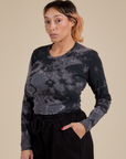 Angled front view of Long Sleeve Baby Tee in Black Magic Waters on Tiara