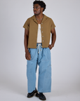 Isaac is wearing Pantry Button-Up in Desert Brown and light wash Denim Drop Pocket Pants