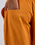 Close up of Kira's hand in the back pocket of Drop Pocket Cargo Pants in Creamsicle Orange
